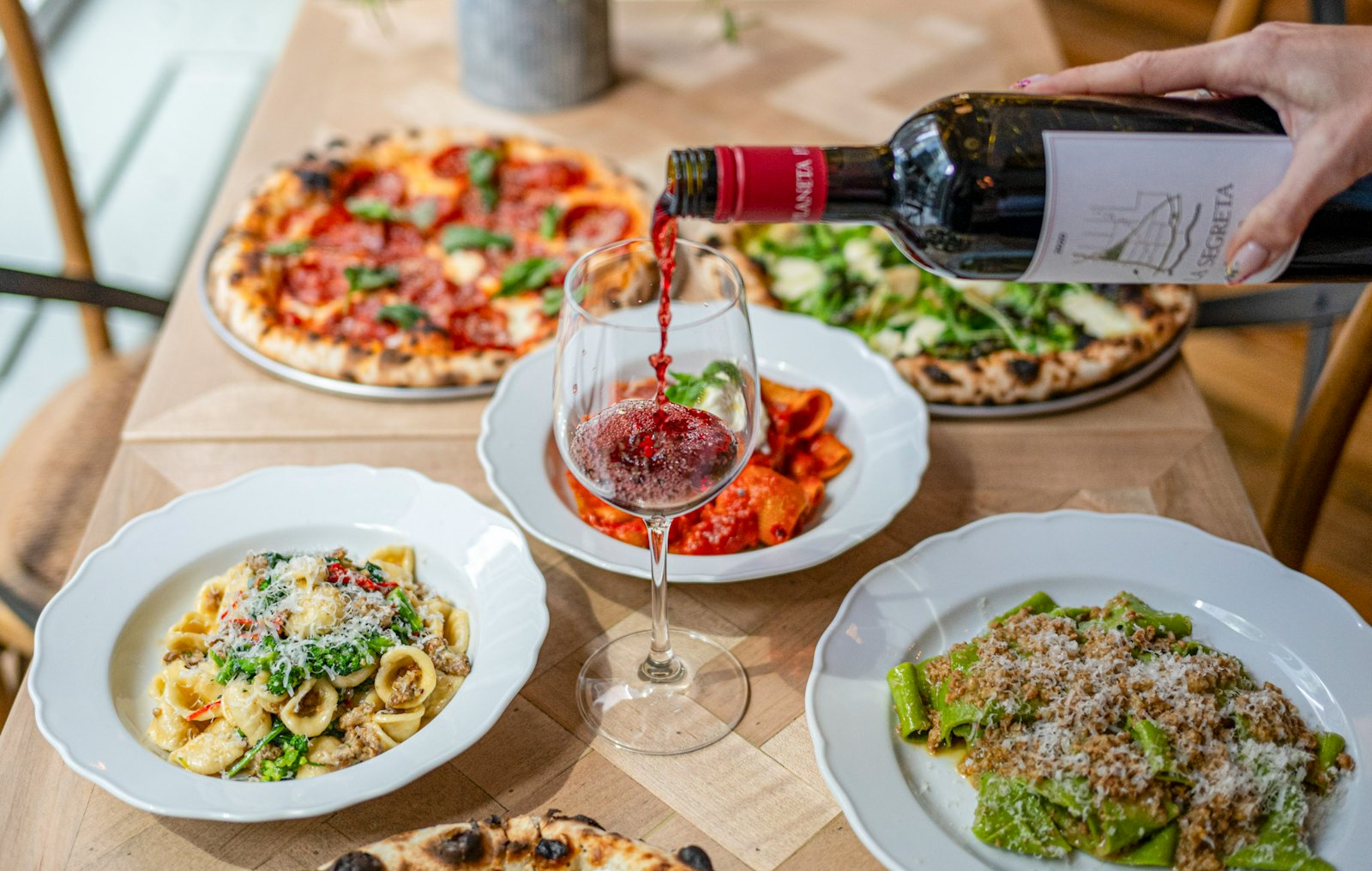 A spread of Rosemary's Midtown's signature dishes with a glass of wine in the foreground.